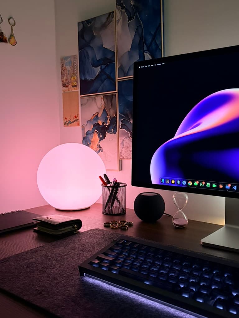 My desk: a monitor, mechanical keyboard, a glowing pink lamp and framed blue abstract art on the wall.